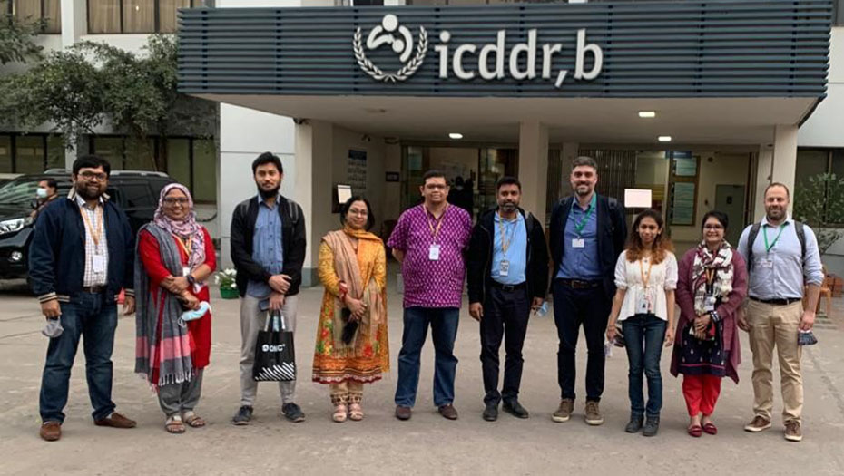 Un groupe de personnes devant le bâtiment de l'icddr,b.