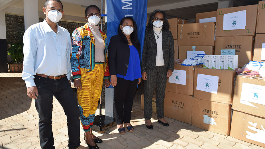 Four people wearing masks in front of boxes marked 