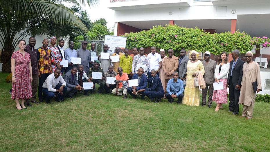 Un groupe de participants en plein air avec des certificats, lors d'un événement de formation GLLP en Guinée.