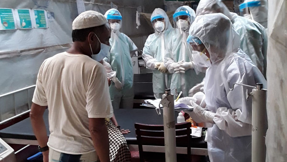 Medical staff in full-body protective suits in a care center during the COVID-19 pandemic.