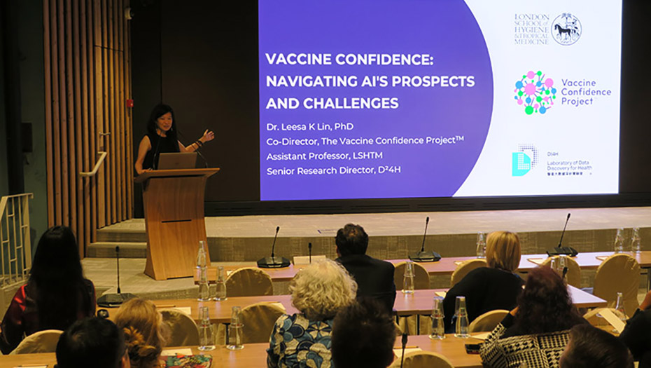 A person presents and projects his or her presentation on a screen at a conference, in front of an audience.