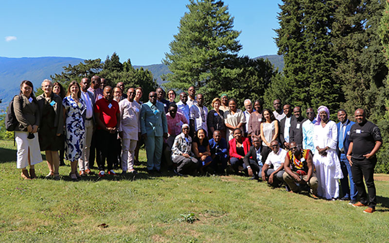 Group of participants posing on a lawn with trees and hills in the background.