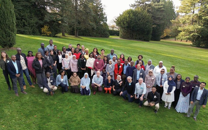 Group of participants posing on a lawn surrounded by trees in a natural landscape.