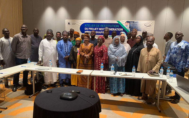 Group of participants standing behind a table with laptops and water bottles in front of a workshop banner.
